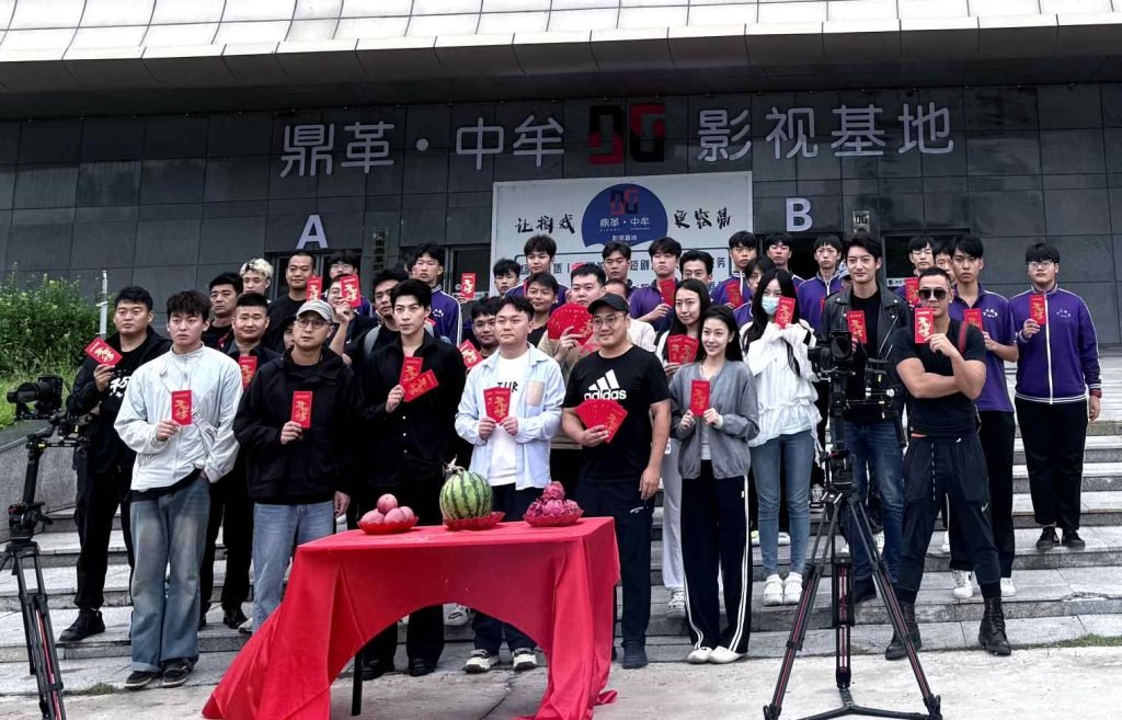 image shows students holding Red Packet and in front of them there is watermelon on the table.